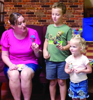 Toddler Music Time instructor Regina Brown shows siblings Parker and Blake Stacy how to use finger puppets during the first Toddler Music Time of the summer held at the Cushing Public Library Monday, June 17. Photo by Raynee Howell.