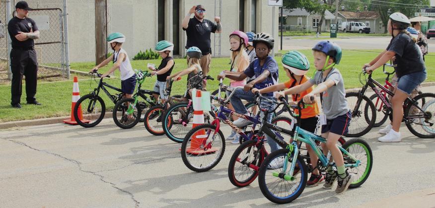 Cushing police and corrections officers teach the recipients of new bikes how to ride safely during the 12th Annual Brandon Hise Memorial Bicycle Rodeo at City Hall Saturday, June 1. Photo by Raynee Howell.